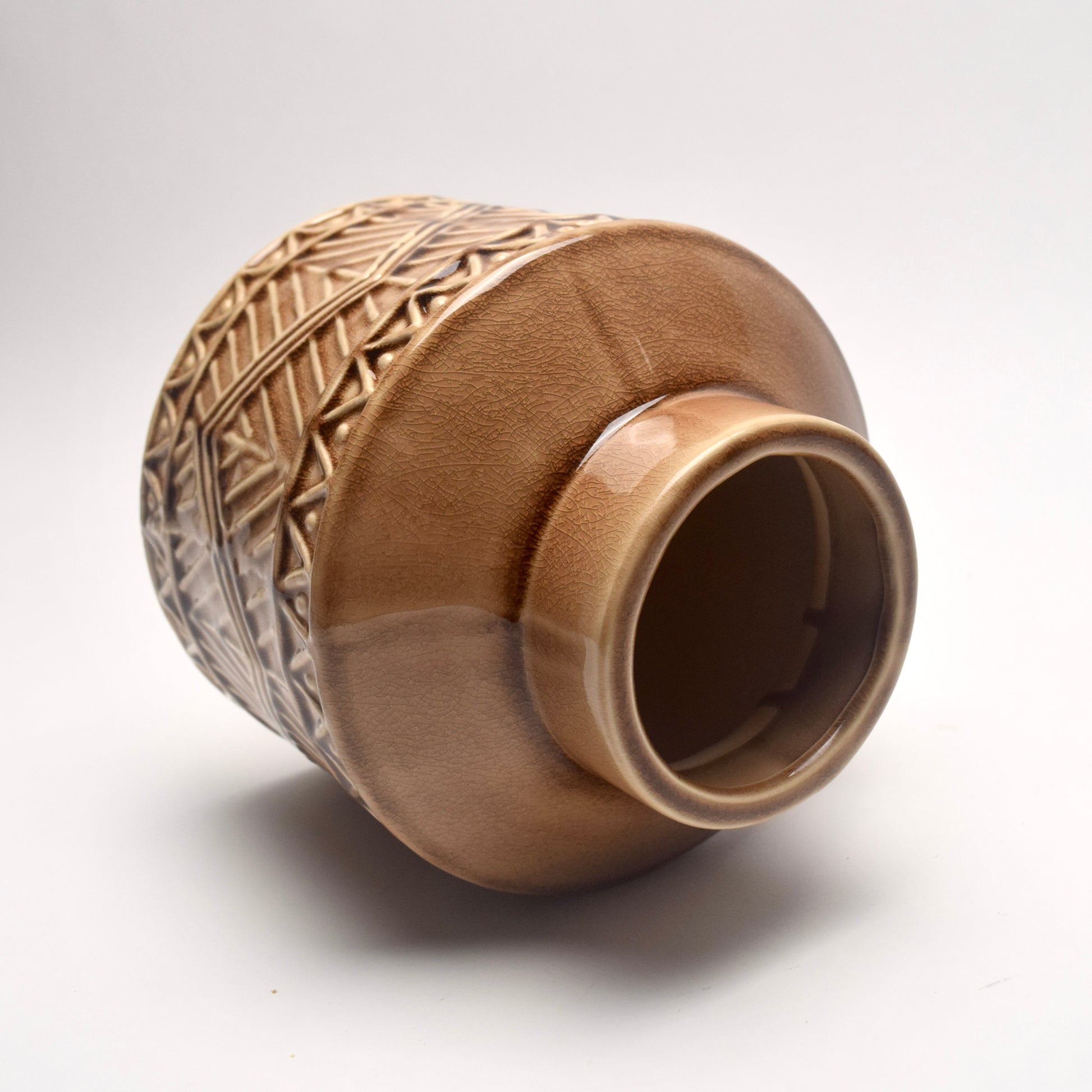 Brown ceramic vase with textured design on a white background