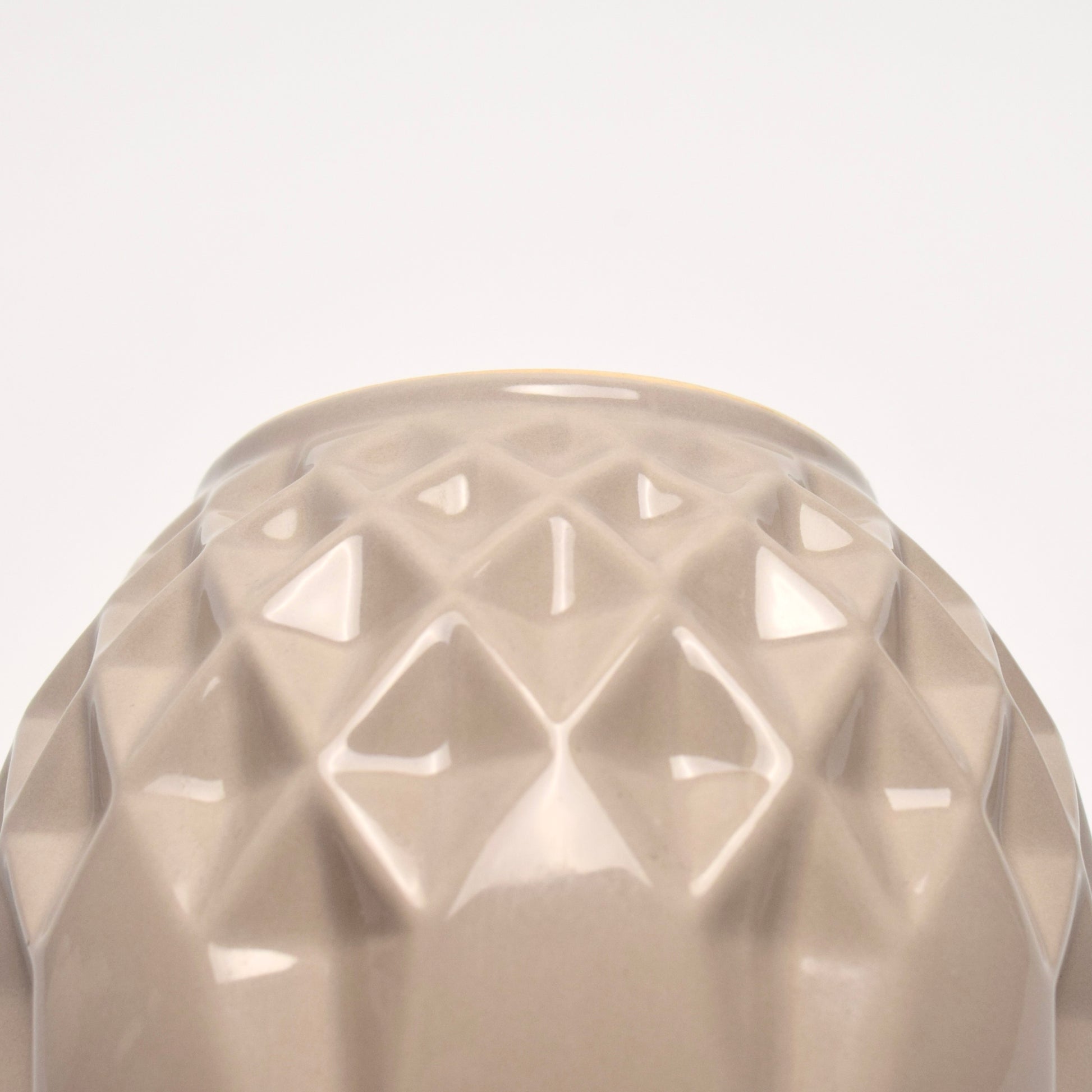 Close-up of a textured beige vase with geometric detailed  pattern. 
