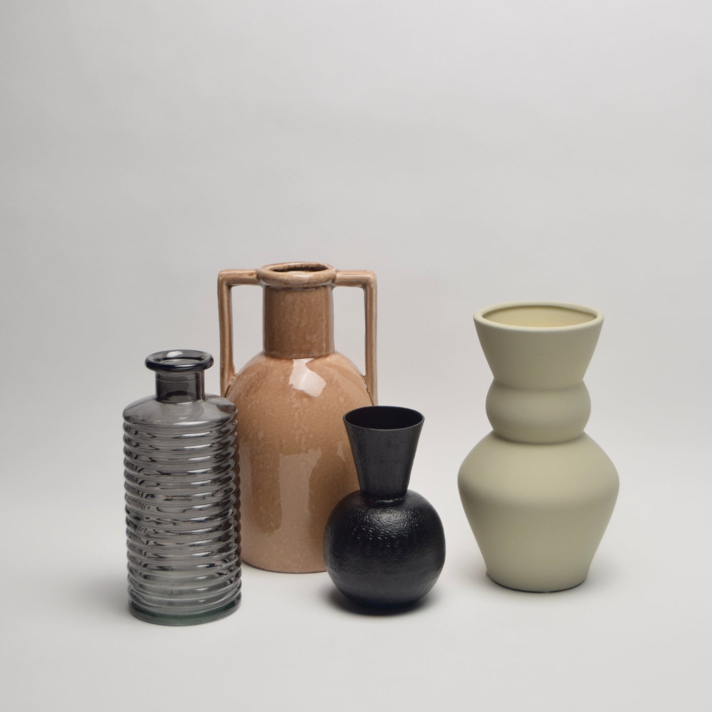 Four ceramic and glass vases of different shapes and colours from black to tan and ecru