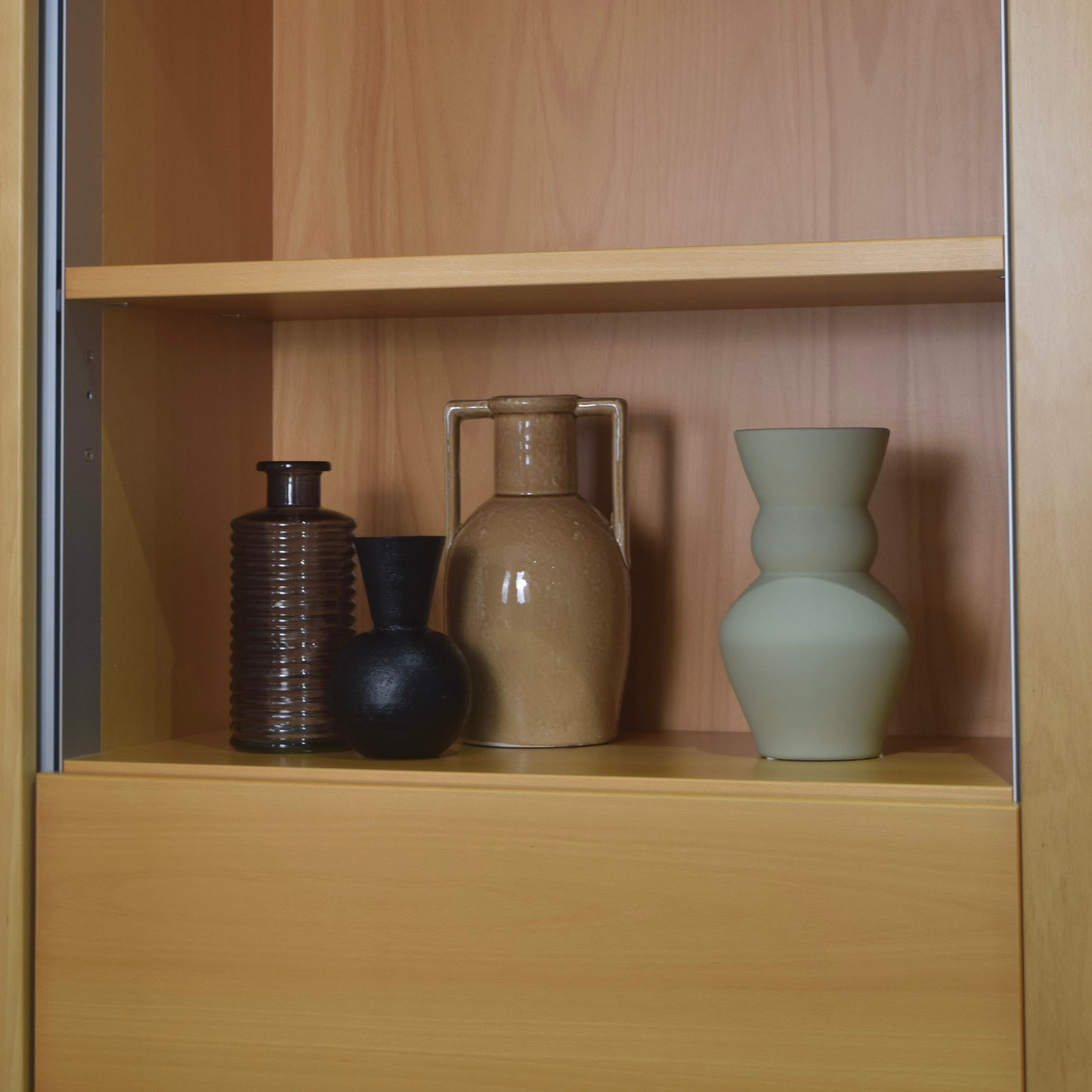 Four ceramic vases on a wooden shelf
